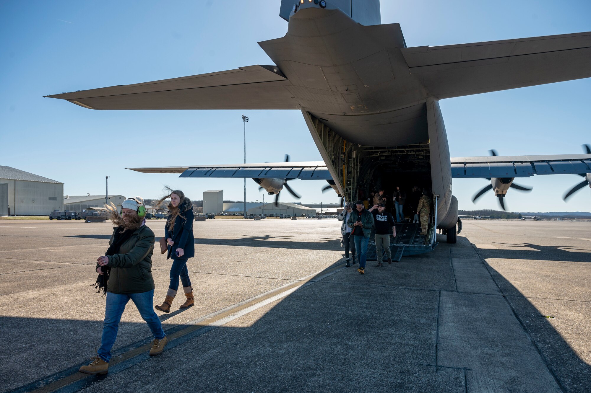 A group of people walk out of a C-130J Super Hercules