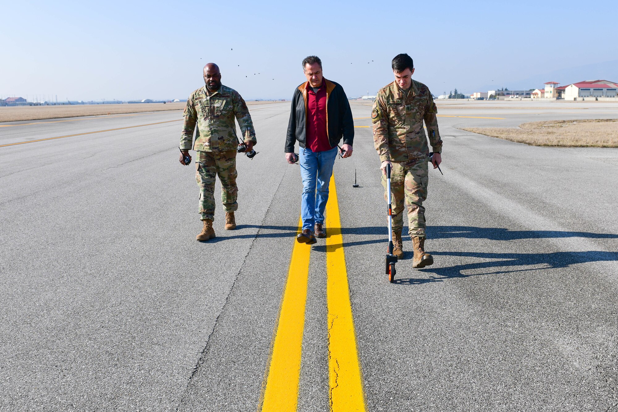Tech. Sgt. Ryan Gibson, 31st Operations Support Squadron Air Traffic Control watch supervisor, Felix Guerra, 31st OSS air traffic automation specialist and U.S. Air Force 1st Lt. Jeffrey Bliss, 31st OSS airfield operations director of operations, measures distance for lights on the flightline at Aviano Air Base, Italy, March 10, 2022. The members trained on airfield management contingency response procedures and used a Phantom AZL-15 lighting kit to simulate landing zones for C-17 Globemasters and C-130 Hercules. The Phantom AZL-15 lighting kit contains approximately 35 LED lamps that are powered with batteries and can be turned on anytime or set up with remotes. (U.S. Air Force photo by Senior Airman Brooke Moeder)