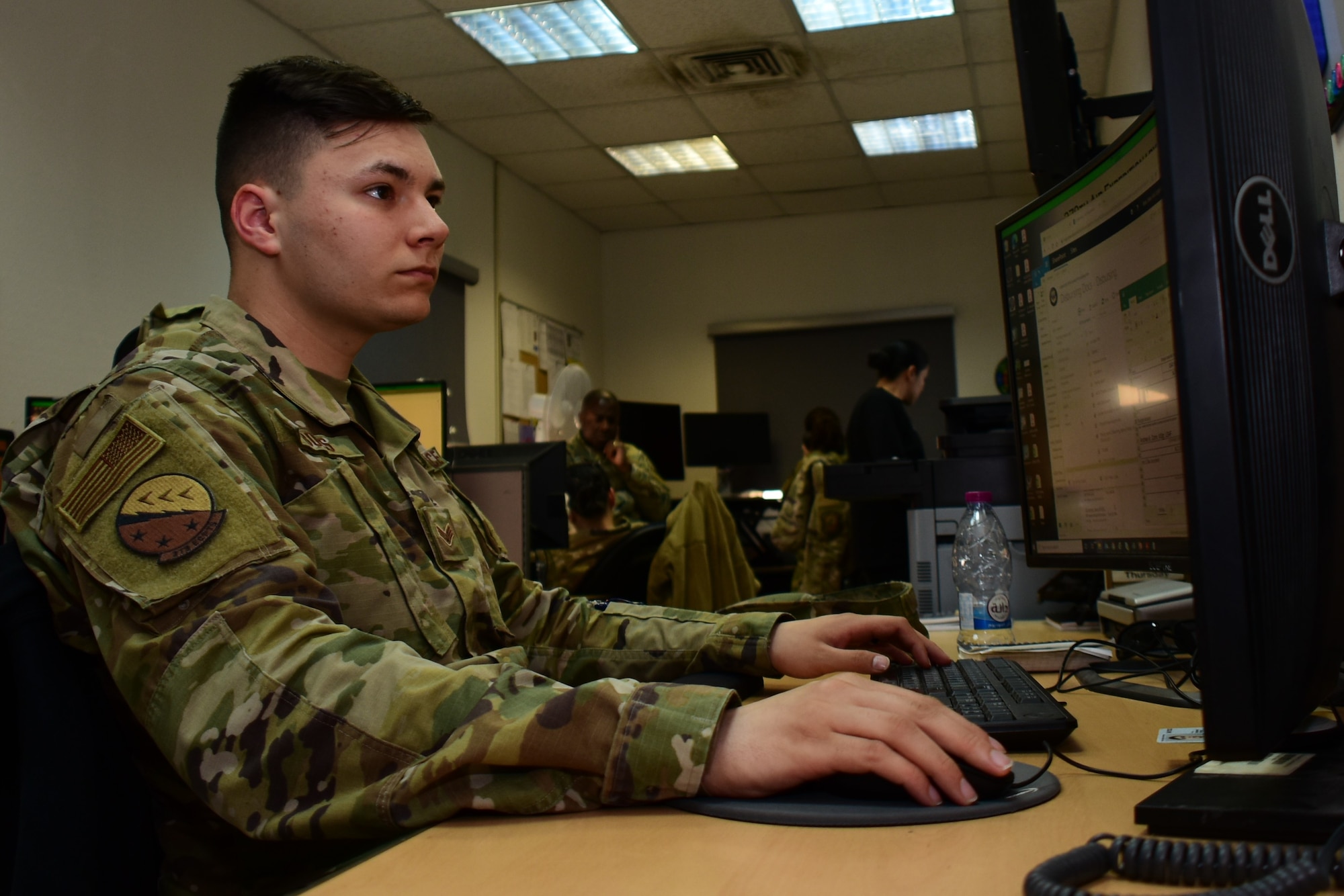 photo of a male Airman sitting at his desk reviewing budget spreadsheets on his computer