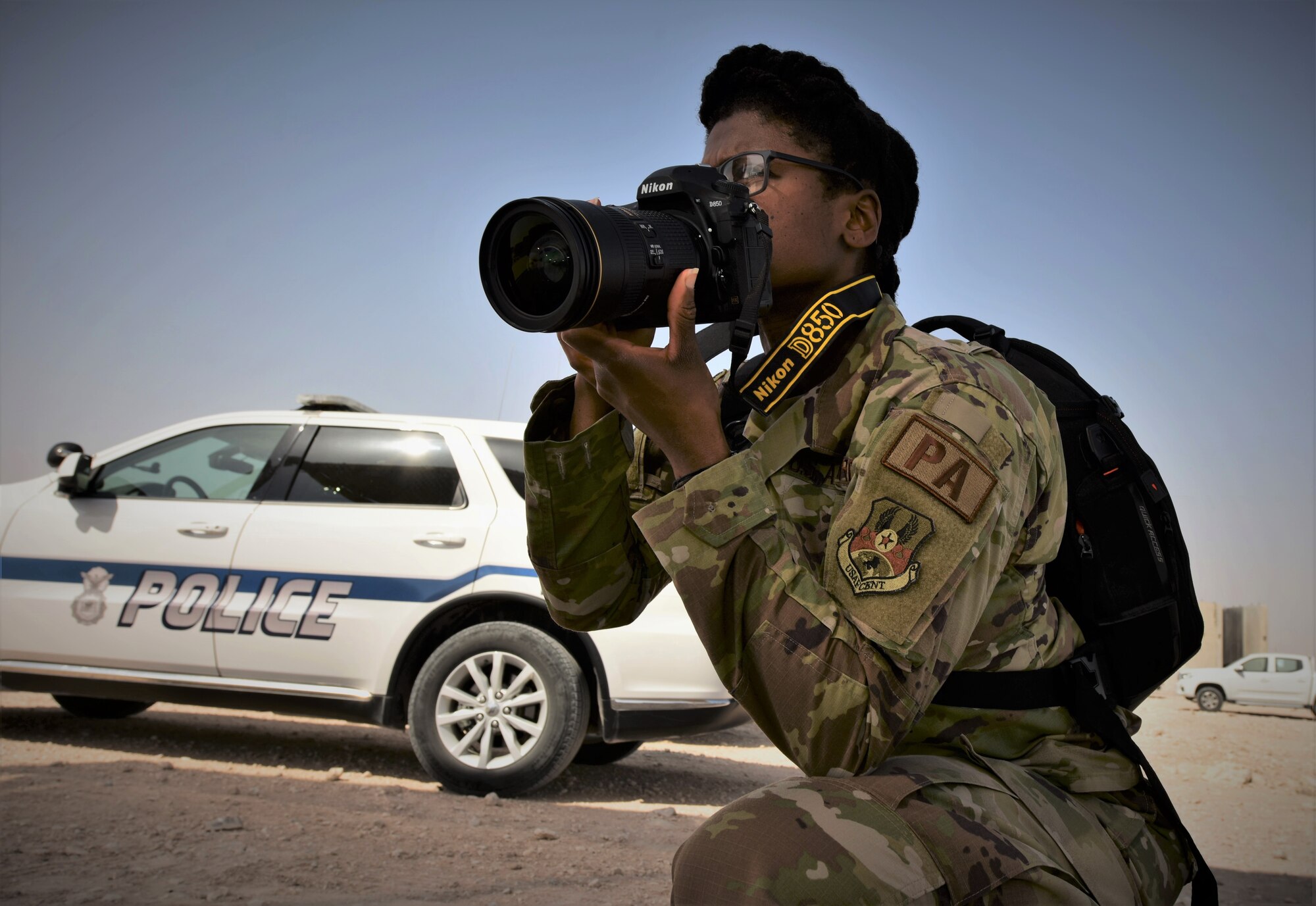 photo of a female military photographer on a knee about to take a photo