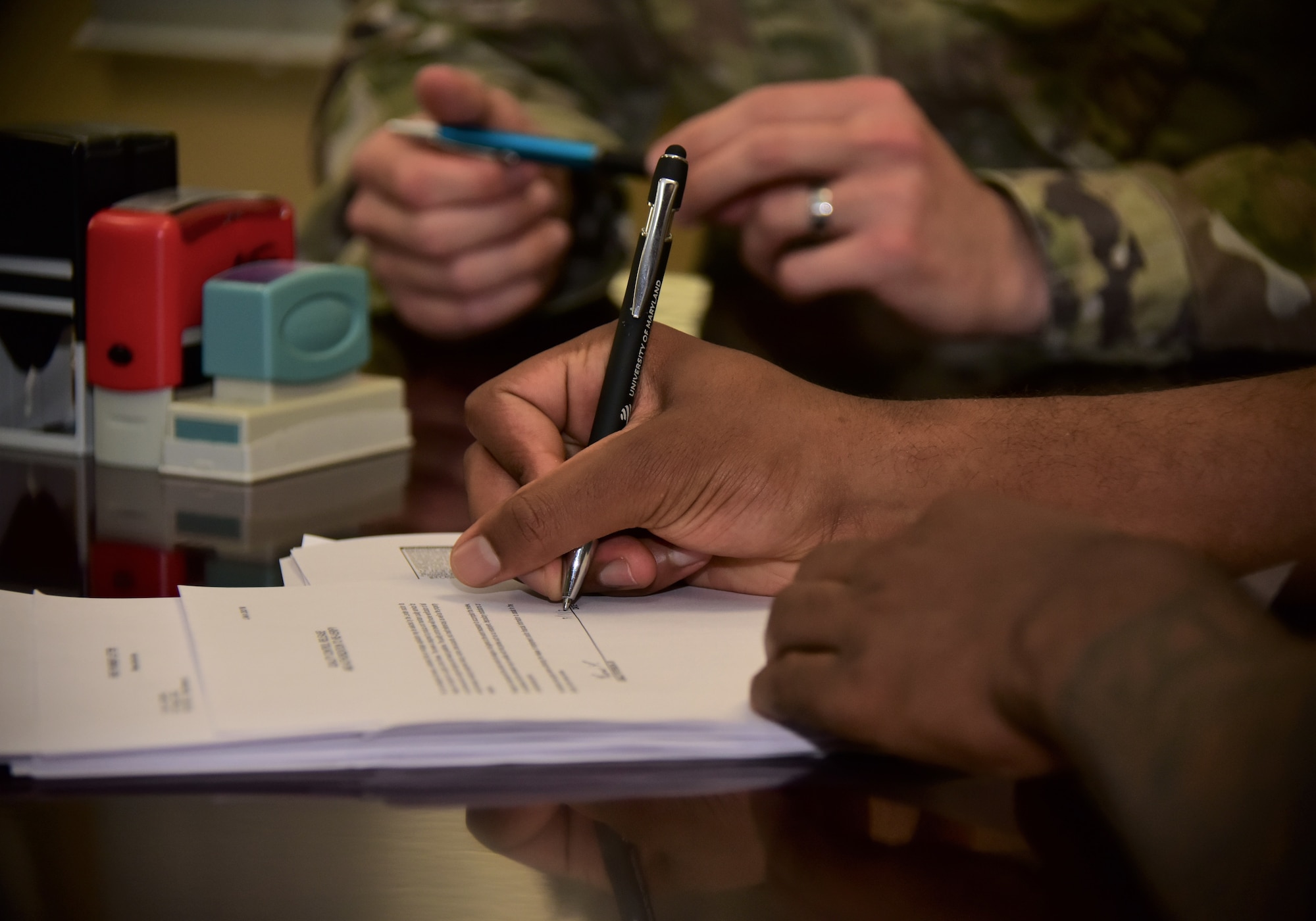 close-up photo of an Airman signing a legal document at a legal office