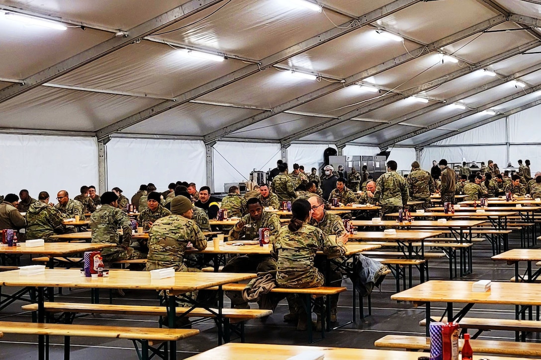 Soldiers eat dinner at a dining facility tent.