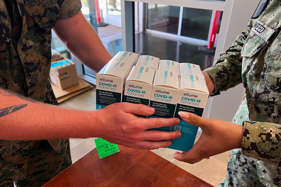 Service members distribute at-home COVID-19 test kits.