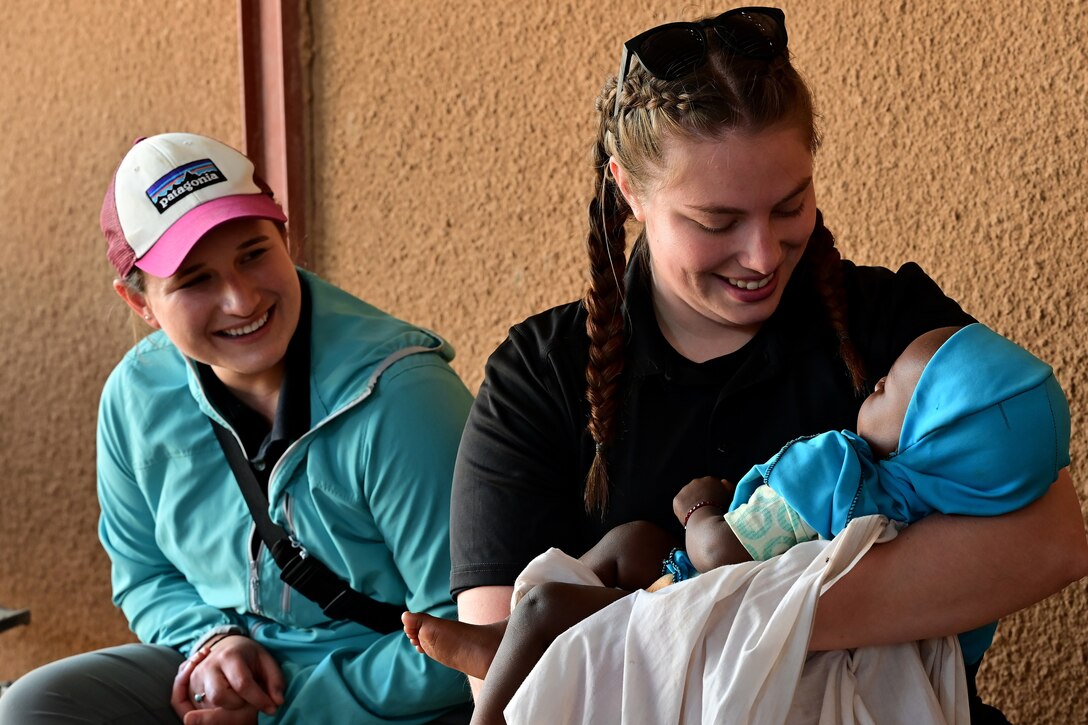 Two women smile as one of them holds a baby.