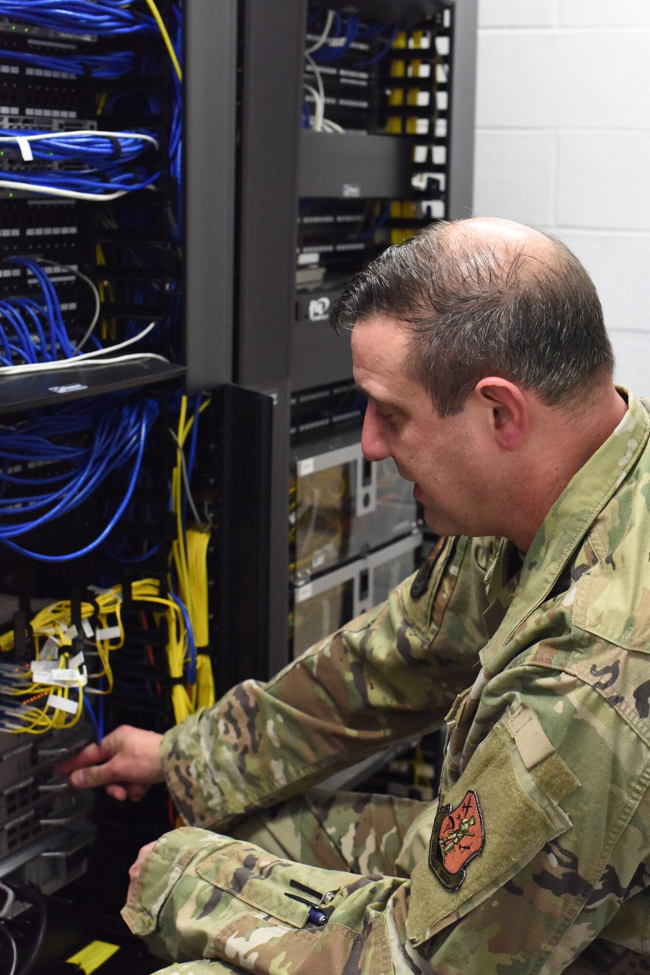 U.S. Air Force Master Sgt. Richard P. Beetstra adjusting cables in communication closet at Francis S. Gabreski Air National Guard Base, Westhampton Beach, N.Y., February 6, 2022. 106th Rescue Wing Communications Flight completed a $1 million Information Technology infrastructure upgrade at the 106th Rescue Wing, Westhampton Beach, N.Y. in February 2022.  (U.S. Air National Guard Photo by Lt. Cheran Campbell)