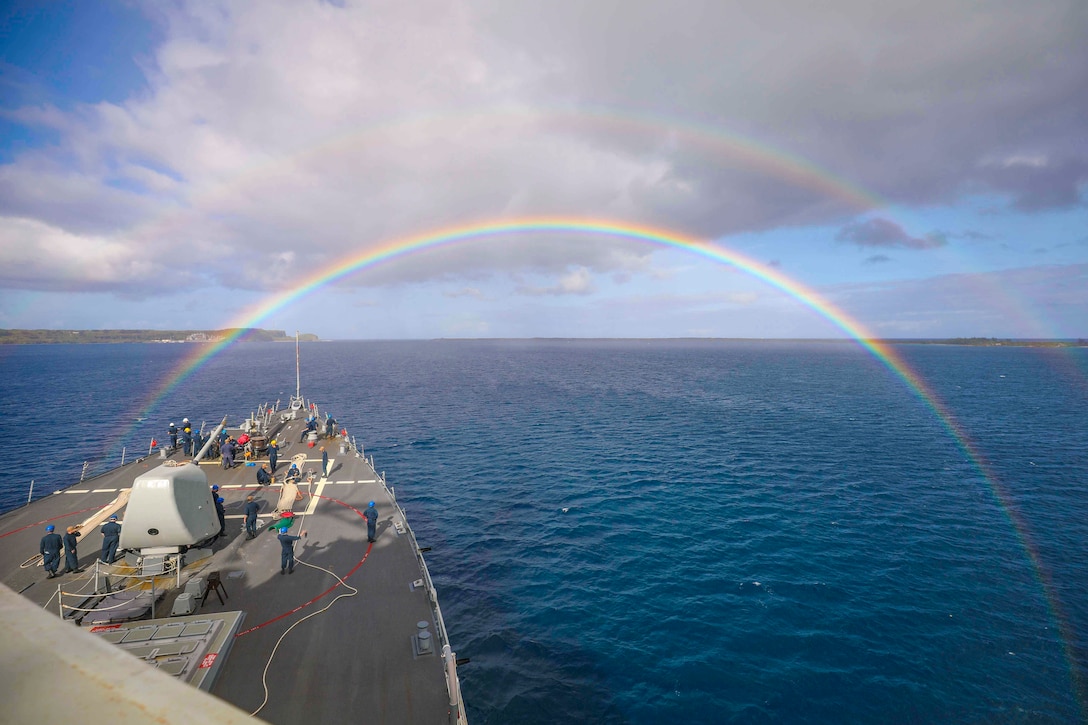 Two rainbows shine above a ship traveling through waters.