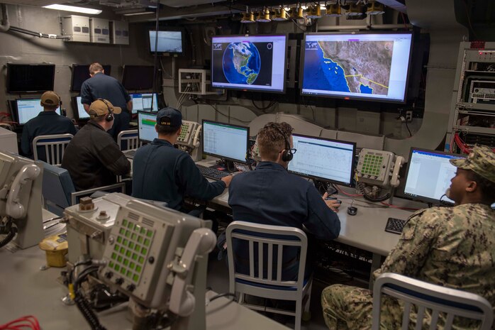 Sailors sitting in chairs look over digital charts