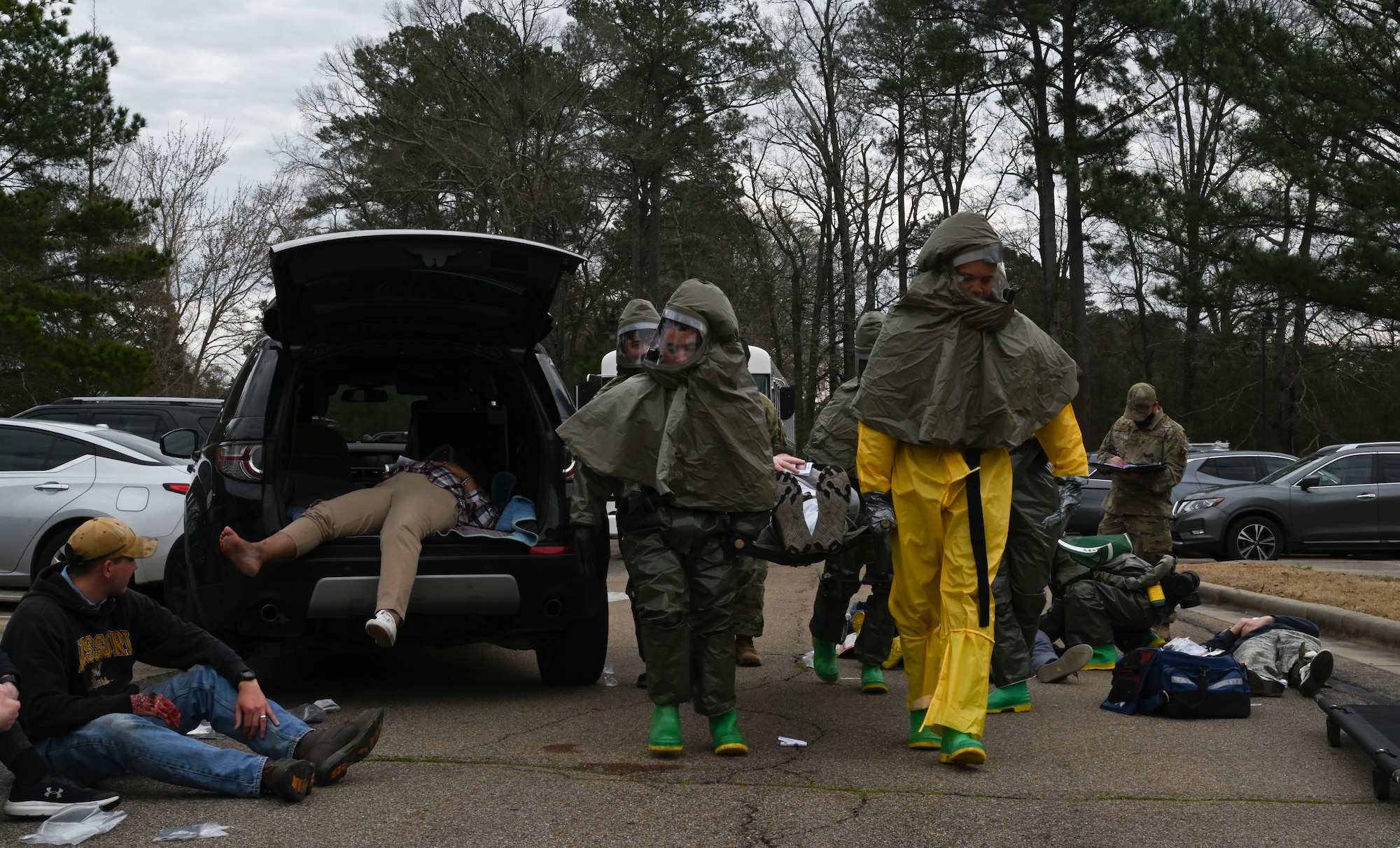 Medics from the 14th Medical Group at Columbus Air Force Base, Miss., carry a volunteer on a stretcher at an exercise on March 11, 2022. While decontaminating and isolating patients, medics are required to wear CBRNE protective gear. (U.S. Air Force photo by Airman 1st Class Jessica Haynie)