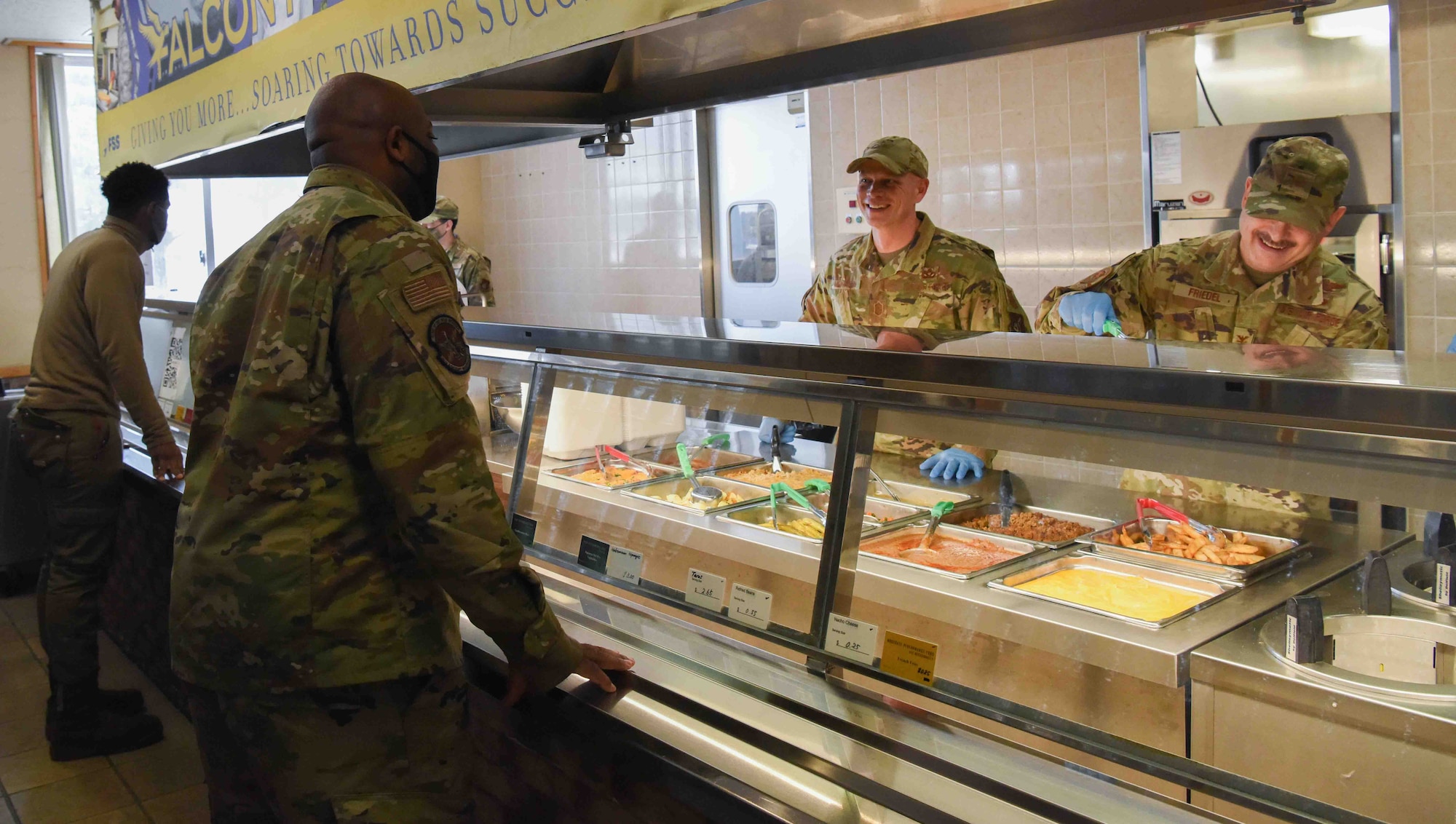 A service member fixes a plate of food to another service member