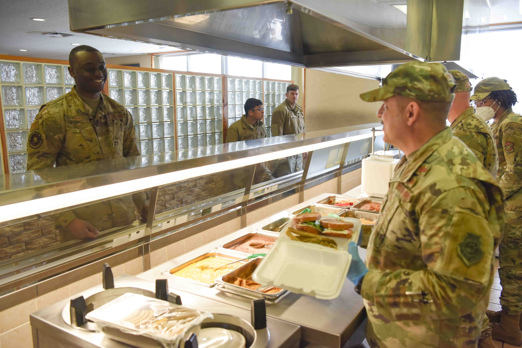 A military member fixes a plate of food for another service member.