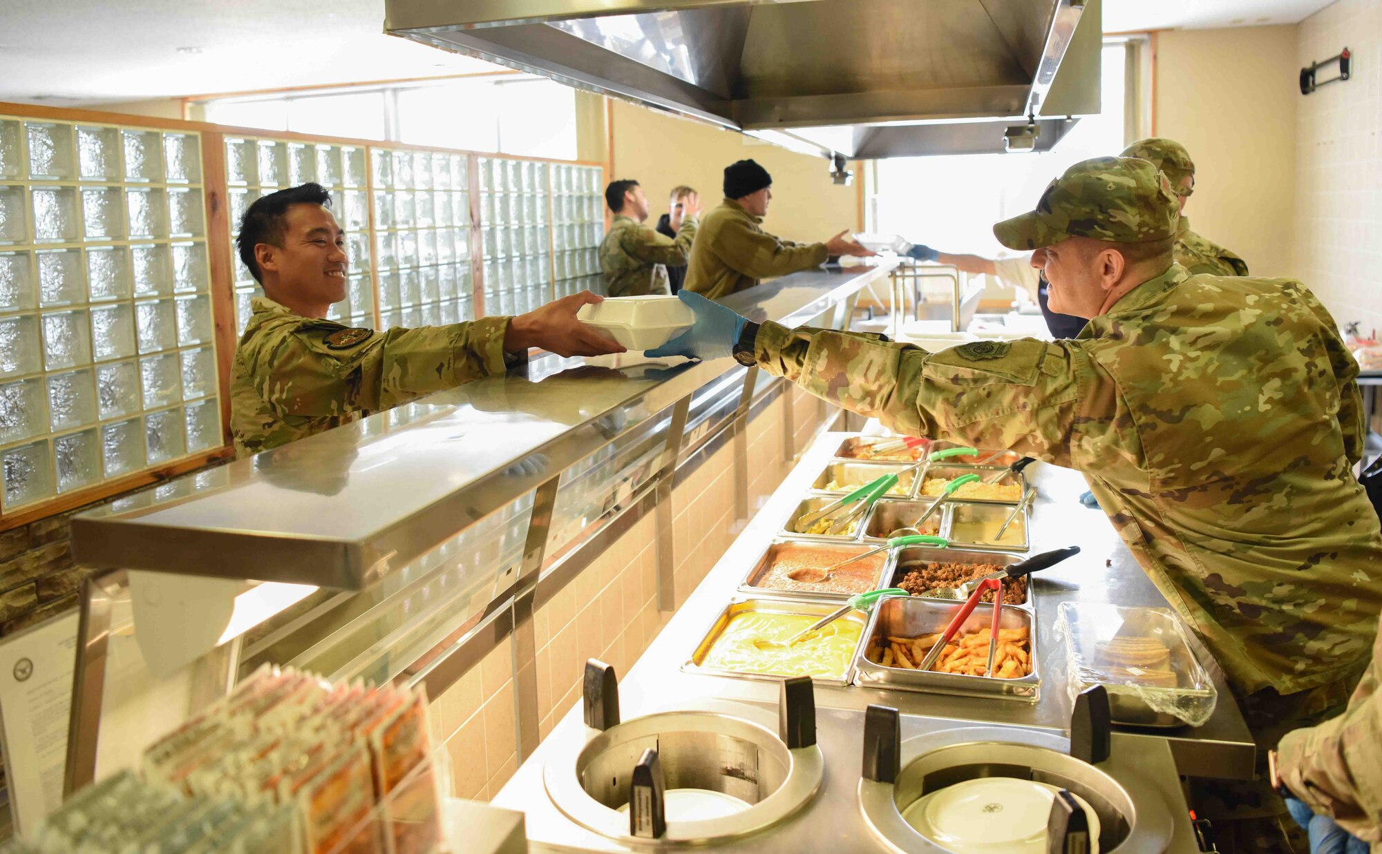 A military member serves food to another military member