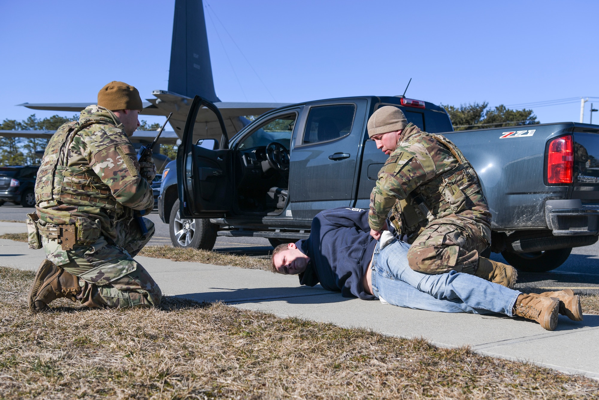 Master Sgt. Nicholas Myers, a 106th Security Forces member, radios to the base defense operations center while Staff Sgt. Noel Ruiz, a 106th Security Forces member, searches a person during an installation breach training exercise at NY Air National Guard’s 106th Rescue Wing, Francis S. Gabreski Air National Guard Base, Westhampton Beach, N.Y., March 4, 2022. During the training, the suspect being detained failed to stop at the base entrance and was subsequently arrested by 106th Security Forces. (U.S. Air National Guard photo by Staff Sgt. Daniel H. Farrell)