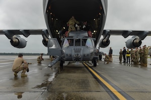 A photo of a helicopter being loaded into a jet.