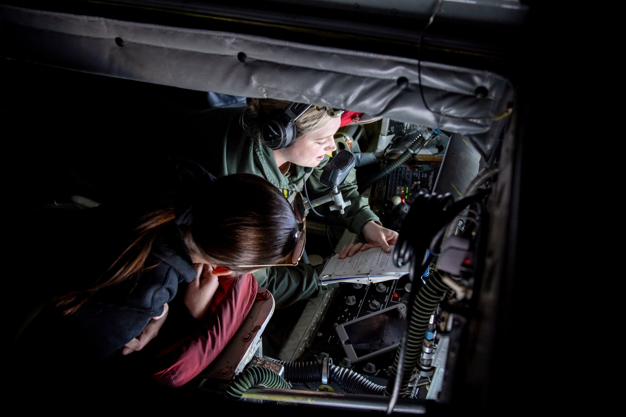 U.S. Air Force Airman 1st Class Cassandra Wesley, a boom operator assigned to the 91st Air Refueling Squadron, reviews a checklist with Evelynn Kite, a Florida State University ROTC cadet, prior to a refueling mission over the Southeastern United States, March 12, 2022. Boom operators have the ability to pump thousands of pounds of fuel to any capable aircraft, thousands of feet above the ground, enabling rapid global mobility. (U.S. Air Force photo by Airman 1st Class Lauren Cobin)