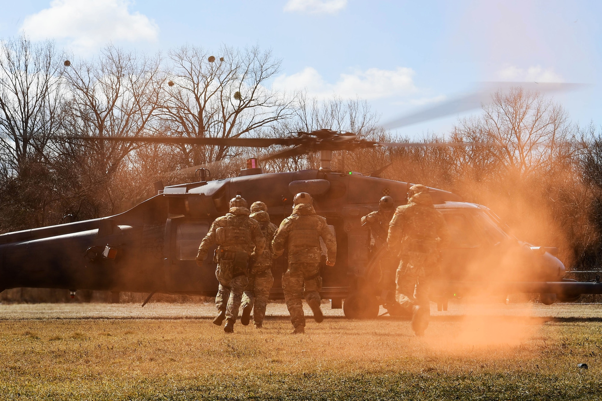 The 51st Commando Battalion Romanian Special Forces run to an HH-60G Pave Hawk, assigned to the 56th Rescue Squadron, in Romania March, 9, 2022. The 57th RQS and the 56th RQS alongside the Royal Marines Commando Mobile Air Operations team with Commando Helicopter Force provided training on how to safely operate around a helicopter to the 51st Commando Battalion Romanian Special Forces. (U.S. Air Force Photo by Senior Airman Noah Sudolcan)