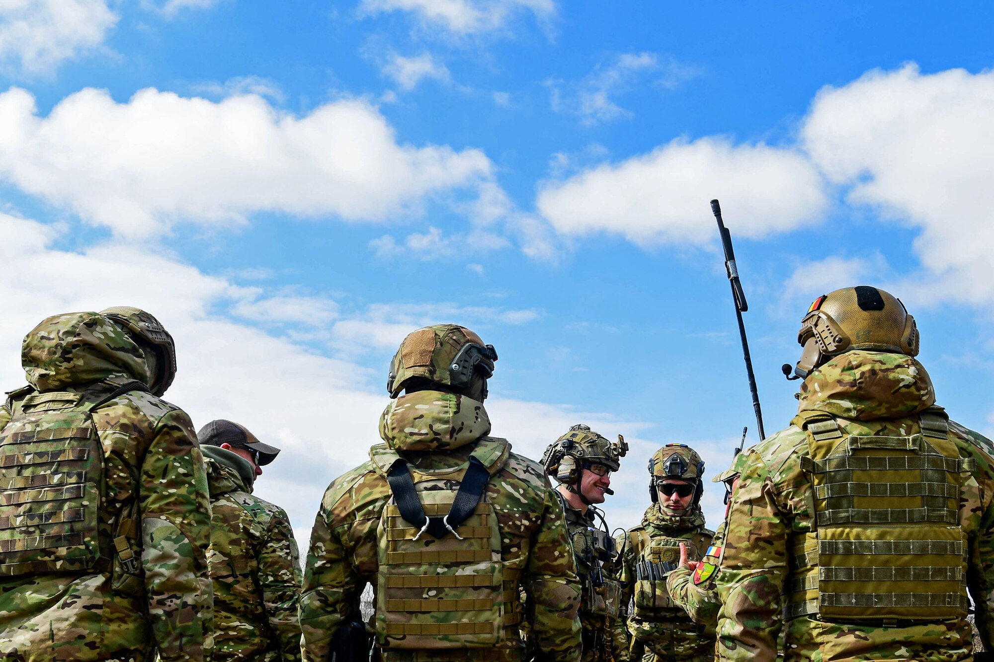 U.S. Air Force 1st Lt. Alexander Mount, 57th Rescue Squadron combat rescue officer, center, speaks with the 51st Commando Battalion Romanian special forces in Romania, March, 9, 2022. Mount assisted the Royal Marines Commando Mobile Air Operations team in teaching safe operations for loading and unloading an HH-60G Pave Hawk assigned to the 56th RQS. (U.S. Air Force photo by Senior Airman Noah Sudolcan)