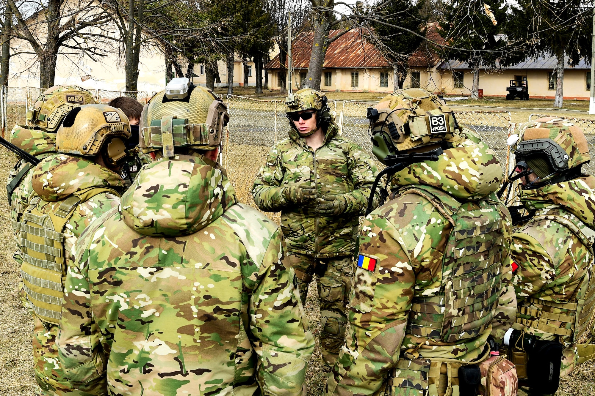 A pararescuemen assigned to the 57th Rescue Squadron, center, briefs 51st Commando Battalion Romanian special forces members in Romania, March 9, 2022. The 57th RQS and the 56th RQS alongside the Royal Marines Commando Mobile Air Operations team with Commando Helicopter Force provided training on how to safely operate around a helicopter to the 51st Commando Battalion Romanian Special Forces. (U.S. Air Force Photo by Senior Airman Noah Sudolcan)