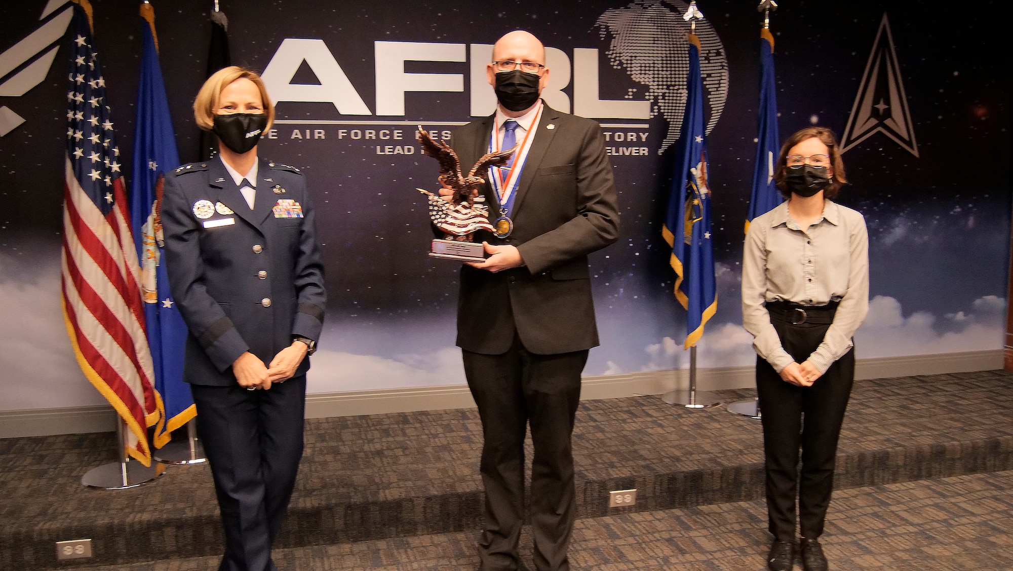 Maj. Gen. Heather Pringle, AFRL commander, and Abby Neal, daughter of Richard Neal, present the AFRL Commander's Cup Richard Neal Special Recognition for a Team award to the AFRL Systems Technology Office-2B team at the AFRL 2021 Annual Awards Ceremony March 1, 2022 at Wright-Patterson Air Force Base, Ohio. Accepting the award on behalf of the team is Ronald Stites. (U.S. Air Force photo/Keith Lewis)