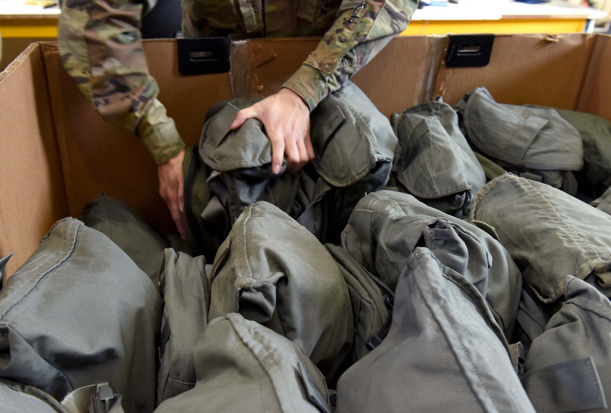 U.S. Air Force Airman 1st Class Kendrew Olboc, 100th Logistics Readiness Squadron Individual Protective Equipment apprentice, stacks old, turned-in gas masks ready to be shipped back to depot in the States at Royal Air Force Mildenhall, England, March 15, 2022. Airmen in the IPE shop support geographically separated units including RAF Croughton, and Stavanger, Norway, and issue all gear for chemical warfare assets to members tasked for deployments and TDYs, ensuring they are issued the correct equipment. (U.S. Air Force photo by Karen Abeyasekere)