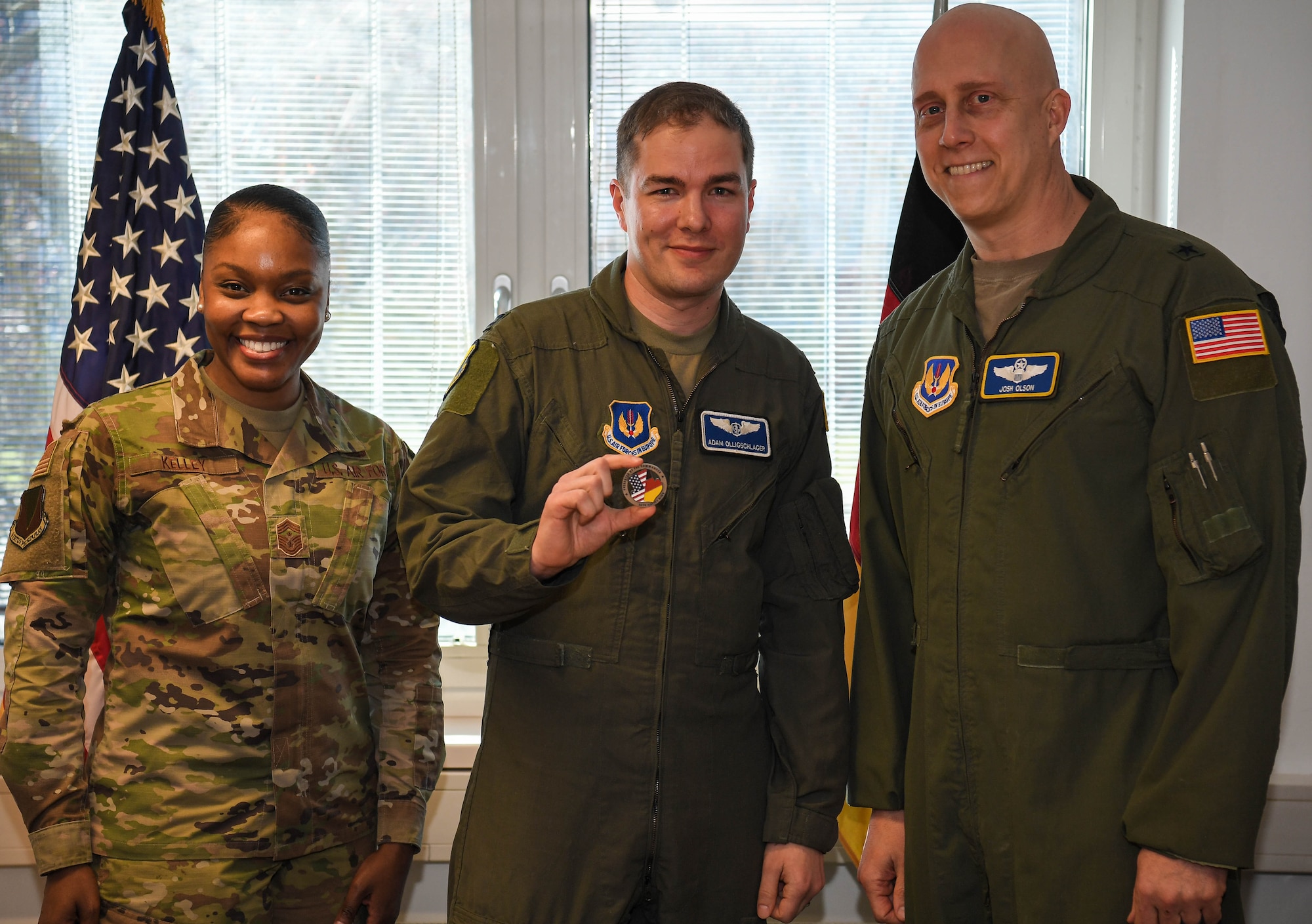 U.S. Air Force Capt. Adam Olligschlager, 86th Airlift Wing plans and programs action officer, center, poses for a photo with the 86th Airlift Wing commander and command chief at Ramstein Air Base, Germany, March 10, 2022. Olligschlager was celebrated as Airlifter of the Week for his outstanding organization and execution of the Secretary of Defense Dispersal Plan. (U.S. Air Force photo by Airman 1st Class Jared Lovett)