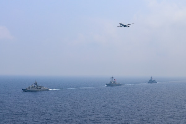 SOUTH CHINA SEA (March 15, 2022) The guided-missile destroyer USS Momsen (DDG 92), Royal Australian Navy Anzac-class frigate HMAS Arunta (FFH 151), and Japan Maritime Self-Defense Force Murasame-class guided missile destroyer JS Yuudachi (DD 103) transit the South China Sea as a U.S. Navy P-8A Poseidon flies over, during a trilateral training event. Momsen is assigned to Commander, Task Force 71/Destroyer Squadron (DESRON) 15, the Navy's largest forward-deployed DESRON and the U.S. 7th Fleet's principal fighting force, and is underway supporting a free and open Indo-Pacific. (U.S. Navy photo by Naval Air Crewman (Helicopter) 3rd Class Regnor Vondedenroth)