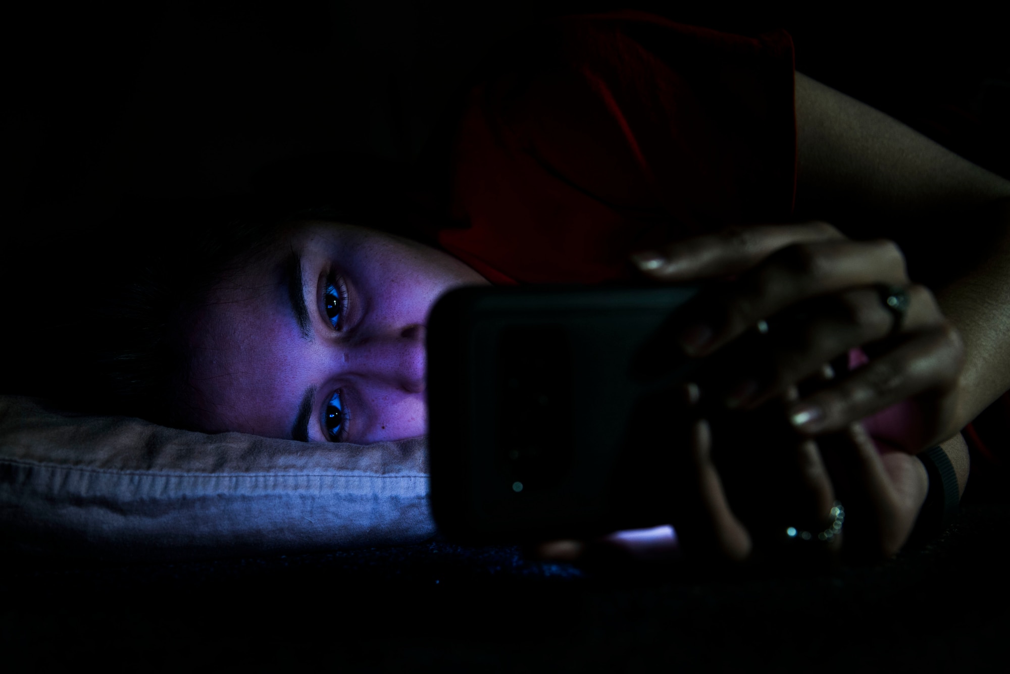 Airman looking at phone in bed.