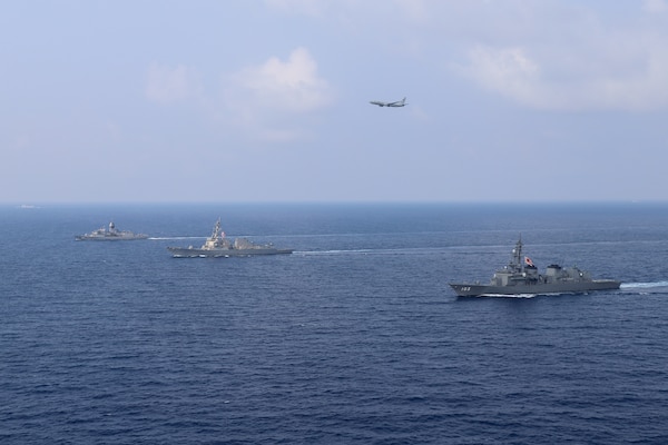 SOUTH CHINA SEA (March 15, 2022) The guided-missile destroyer USS Momsen (DDG 92), the Royal Australian Navy Meko-class frigate HMAS Arunta (FFH 151), and the Japan Maritime Self-Defense Force guided-missile destroyer JS Yuudachi (DD 103) transit the South China Sea while a P-8A Poseidon flies by during a trilateral training event. Momsen is assigned to Commander, Task Force 71/Destroyer Squadron (DESRON) 15, the Navy's largest forward-deployed DESRON and the U.S. 7th Fleet's principal fighting force, and is underway supporting a free and open Indo-Pacific. (U.S. Navy photo by Naval Air Crewman (Helicopter) 1st Class Justin Sherman)