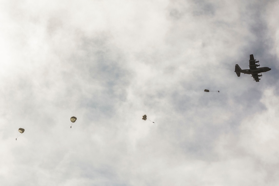 Service members free fall with parachutes after jumping out an aircraft.