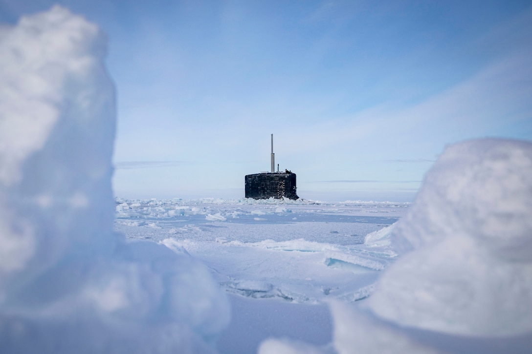 The top of a submarine is seen amid an icy sea.