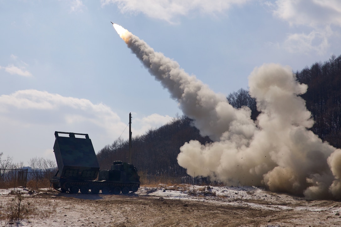 Soldiers fire a rocket next to a truck in a field.