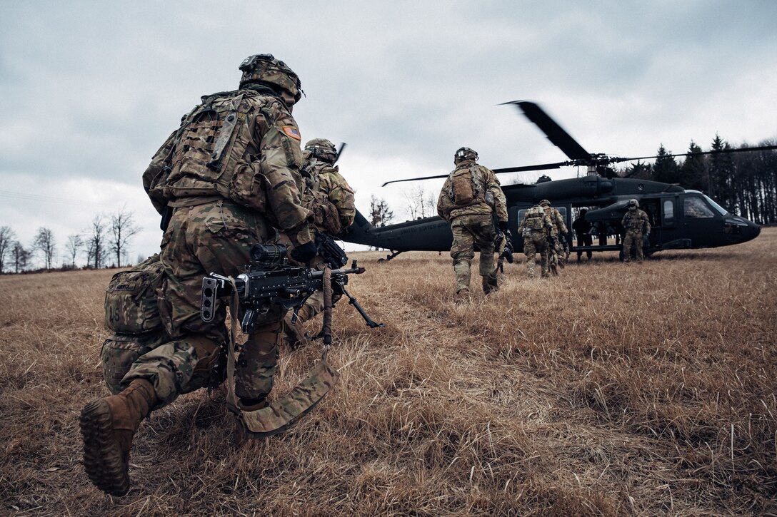 Soldiers run toward a helicopter.