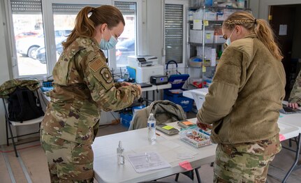 two soldiers prepare a syringe for vaccinations.