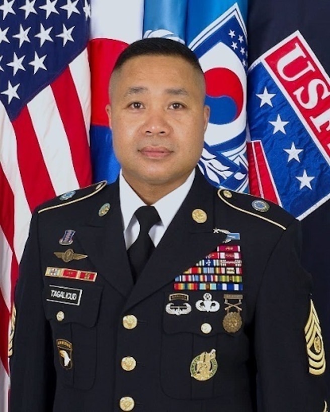 Portrait of U.S. Army Command Sgt. Major Walter Tagalicud in dress uniform, standing in front of the U.S. flag, South Korean flag, UNC flag, CFC flag and USFK flag.