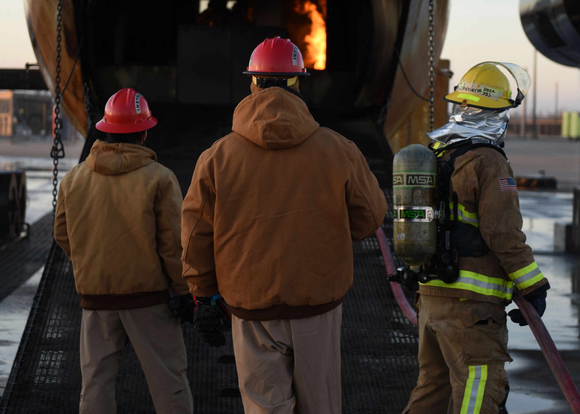 Service members of the 312th Training Squadron extinguish a fire on an aircraft fire simulator at the Louis F. Garland Department of Defense Fire Academy, Goodfellow Air Force Base, March 9, 2022. The controlled fires created by the simulator can reach up to 1,200 degrees Fahrenheit. (U.S. Air Force photo by Airman 1st Class Sarah Williams)