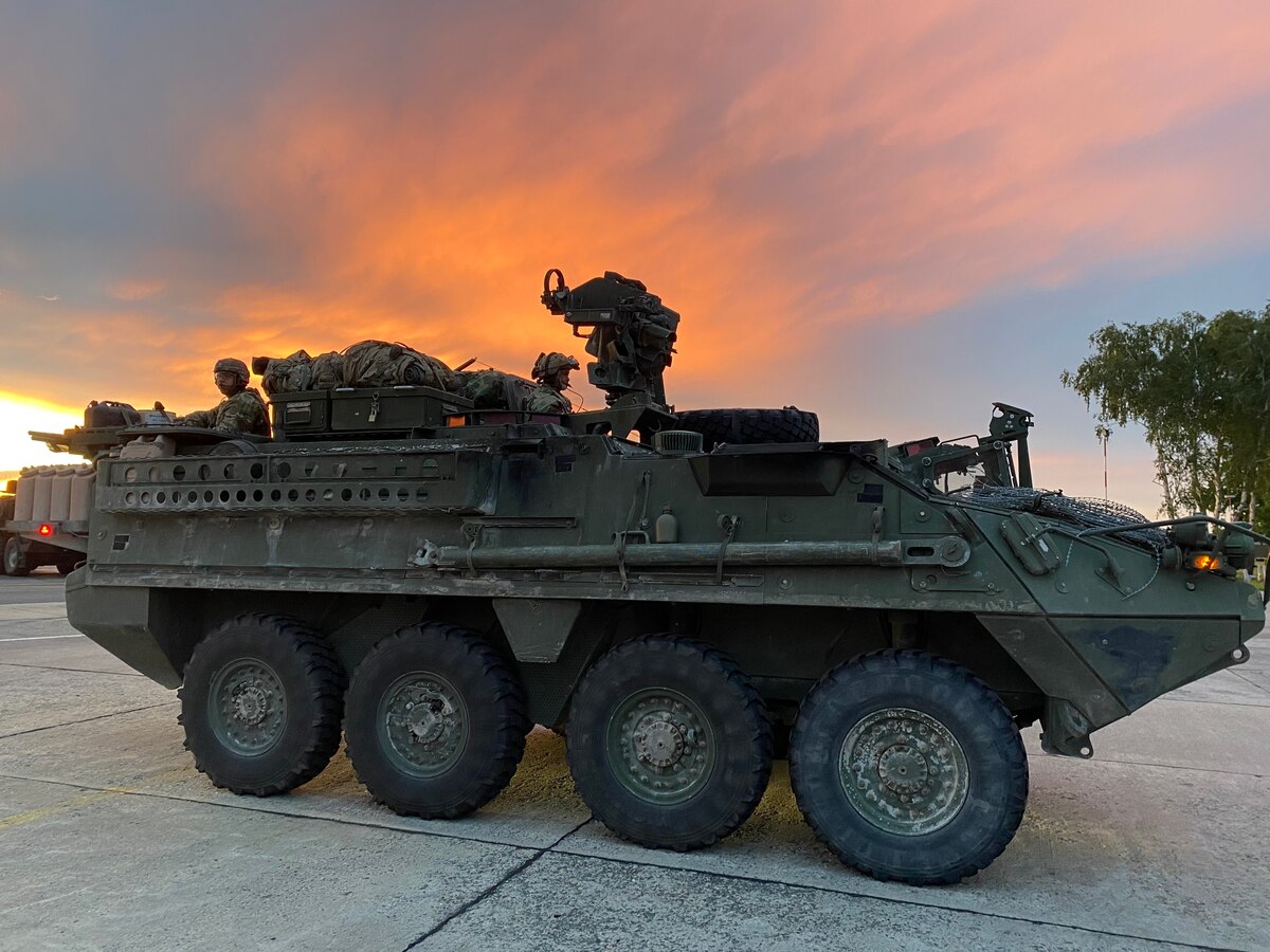 A combat vehicle sits on a cement slab at dusk.