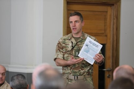 Lt. Col. Timothy James, deputy director defense security corps, displays the Combined Joint Task Force – Operation Inherent Resolve’s (CJTF-OIR’s) updated newsletter during the defense attaché forum in Baghdad, Iraq, March 17, 2022. The defense attaché forum serves as an opportunity to build-relationships among Global Coalition members, and as a gateway to discuss topics pertaining to the enduring defeat of Da’esh including CJTF – OIR’s progress and areas of needed improvement. (U.S. Army photo by Staff Sgt. Bree-Ann Ramos-Clifton)