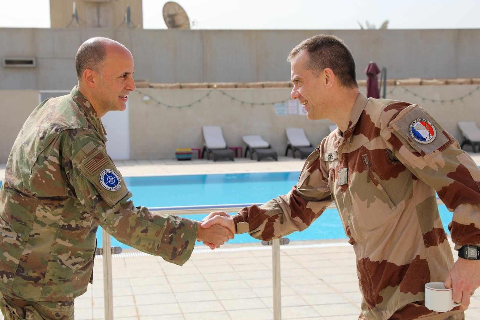 U.S. Air force Brig. Gen. Don Bevis, Senior commanding North Atlantic Treaty Organization – mission Iraq and a French coalition member shake hands before the defense attaché forum convenes in Baghdad, Iraq, March 17, 2022. The defense attaché forum serves as an opportunity to build-relationships among Global Coalition members, and as a gateway to discuss topics pertaining to the enduring defeat of Da’esh including Combined Joint Task Force – Operation Inherent Resolve’s progress and areas of needed improvement. (U.S. Army photo by Staff Sgt. Bree-Ann Ramos-Clifton)