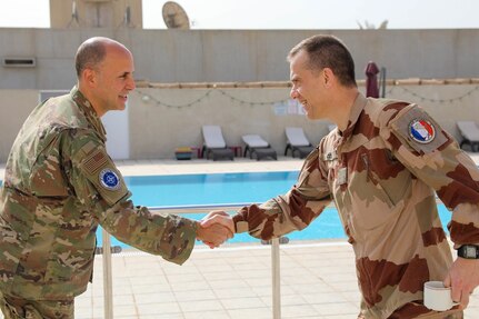 U.S. Air force Brig. Gen. Don Bevis, Senior commanding North Atlantic Treaty Organization – mission Iraq and a French coalition member shake hands before the defense attaché forum convenes in Baghdad, Iraq, March 17, 2022. The defense attaché forum serves as an opportunity to build-relationships among Global Coalition members, and as a gateway to discuss topics pertaining to the enduring defeat of Da’esh including Combined Joint Task Force – Operation Inherent Resolve’s progress and areas of needed improvement. (U.S. Army photo by Staff Sgt. Bree-Ann Ramos-Clifton)