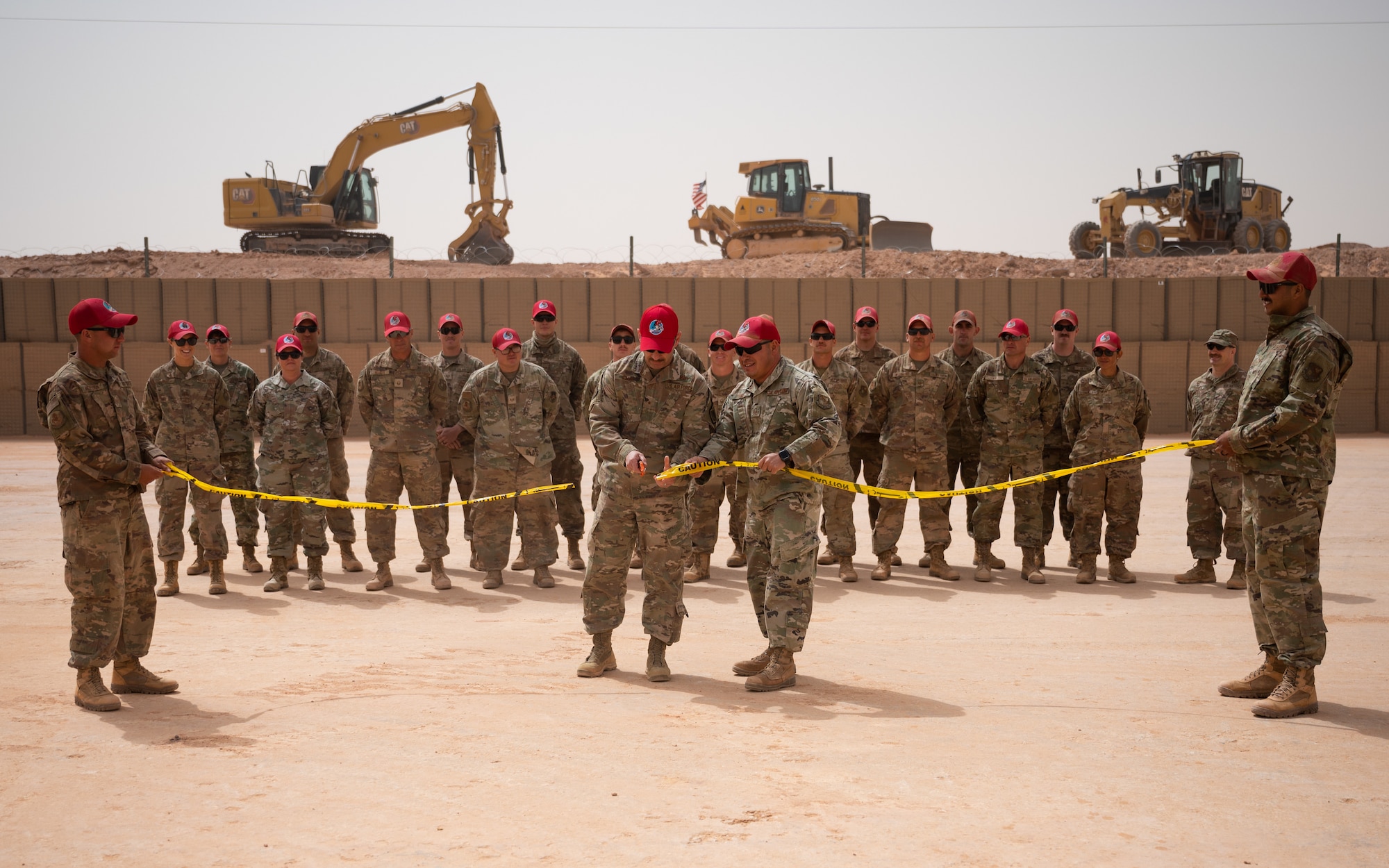 Brig. Gen. Robert Davis, 378th Air Expeditionary Wing commander, and Airmen of the 557th Expeditionary Red Horse Squadron participate in a ribbon cutting ceremony at Prince Sultan Air Base, Kingdom of Saudi Arabia, March 16, 2022. The ribbon cutting ceremony was held to celebrate the expansion of PSAB's munition storage area. (U.S. Air Force photo by Senior Airman Jacob B. Wrightsman)