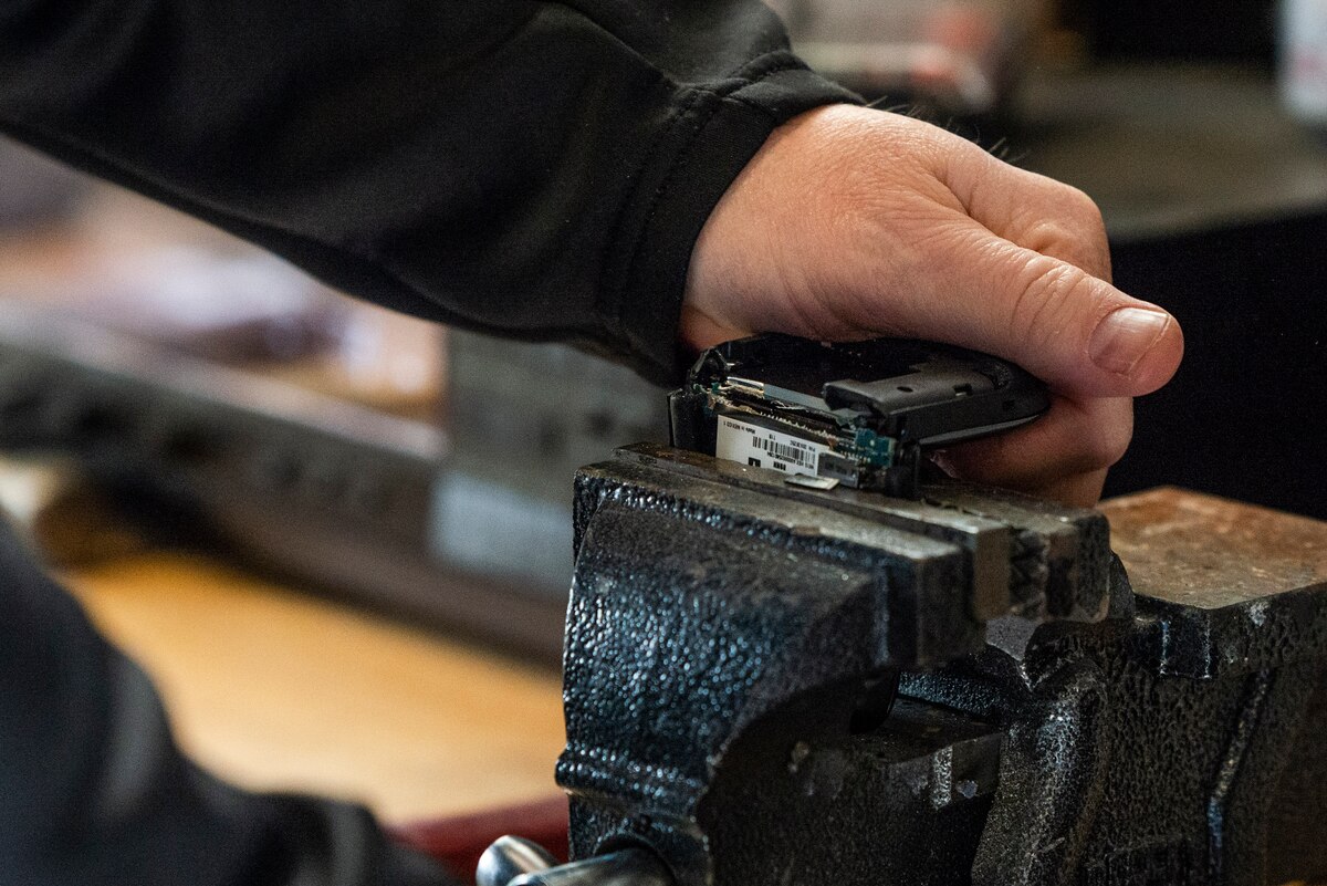 A technician destroys a cellphone during Classified Cleanout Day