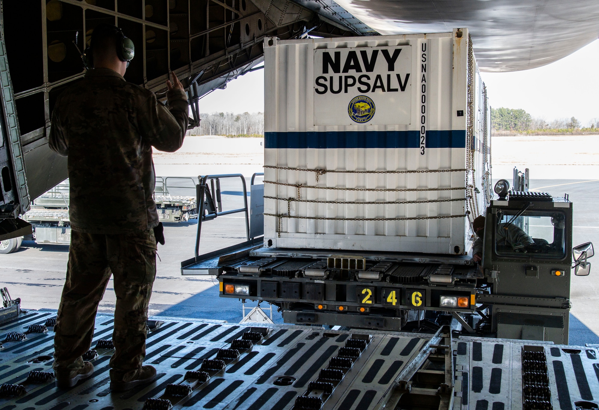 Airman 1st Class Dylan Holtzclaw, 9th Airlift Squadron loadmaster, marshals a cargo loader driven by Senior Airman Martin Riveracandelario, 436th Aerial Port Squadron ramp specialist, at the aft loading ramp of a C-5M Super Galaxy on Dover Air Force Base, Delaware, Feb. 8, 2022. The C-5M transported cargo owned by U.S. Navy Supervisor of Salvage and Diving (SUPSALV), Naval Sea Systems Command. (U.S. Air Force photo by Roland Balik)