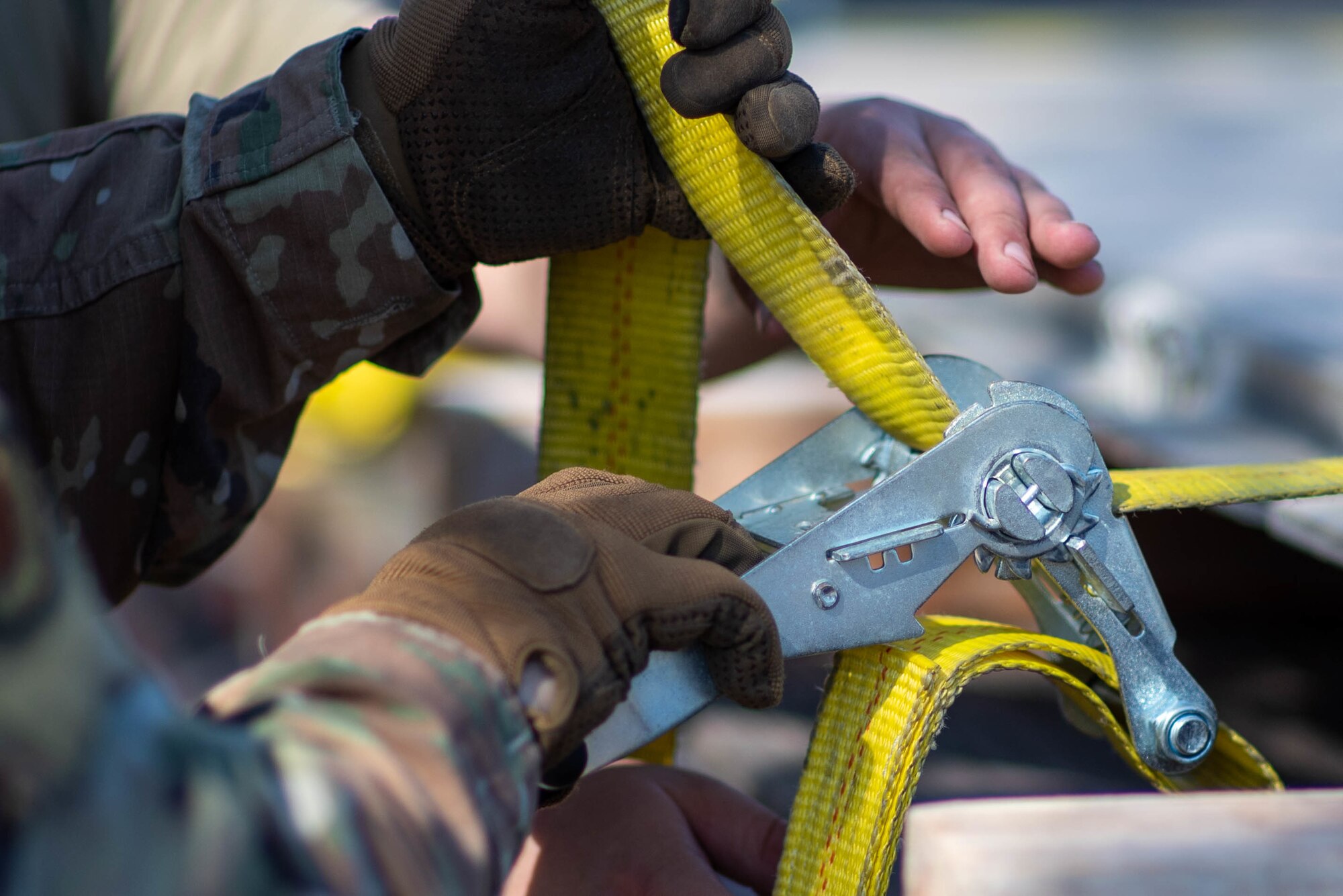 U.S. Air Force Airman 1st Class Corbin Willoughby, 375th Logistics Readiness Squadron ground transportation operator, ratchets a cargo strap on a semitruck on Scott Air Force Base, Illinois, March 16, 2022. Loading cargo for the readiness rehearsal simulated real world operations for 375th LRS ground transportation operators. (U.S. Air Force photo by Airman 1st Class Violette Hosack)