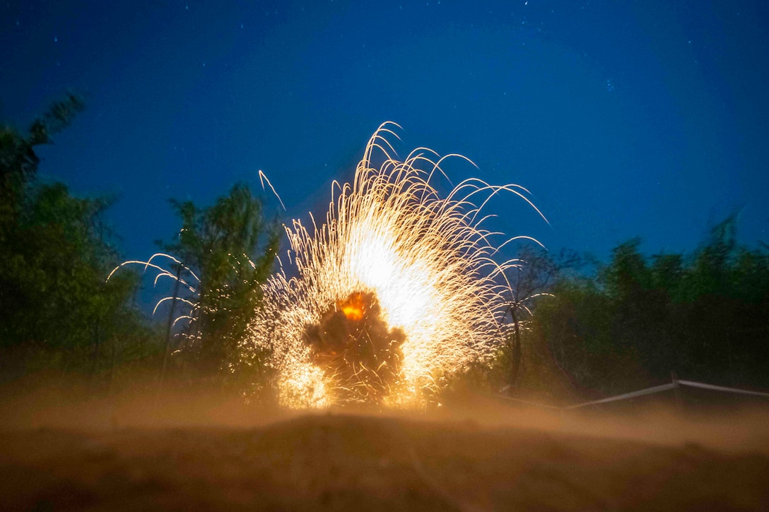 Sparks fly around a soldier at night.