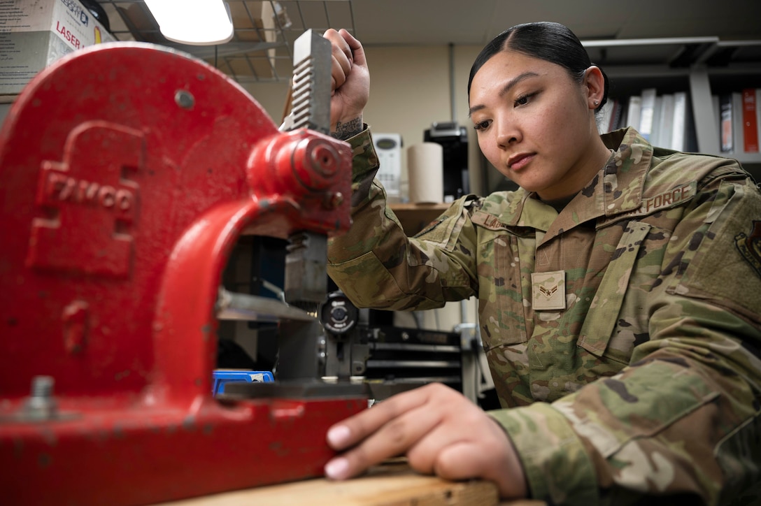 An airman uses a machine to build a part of a door.