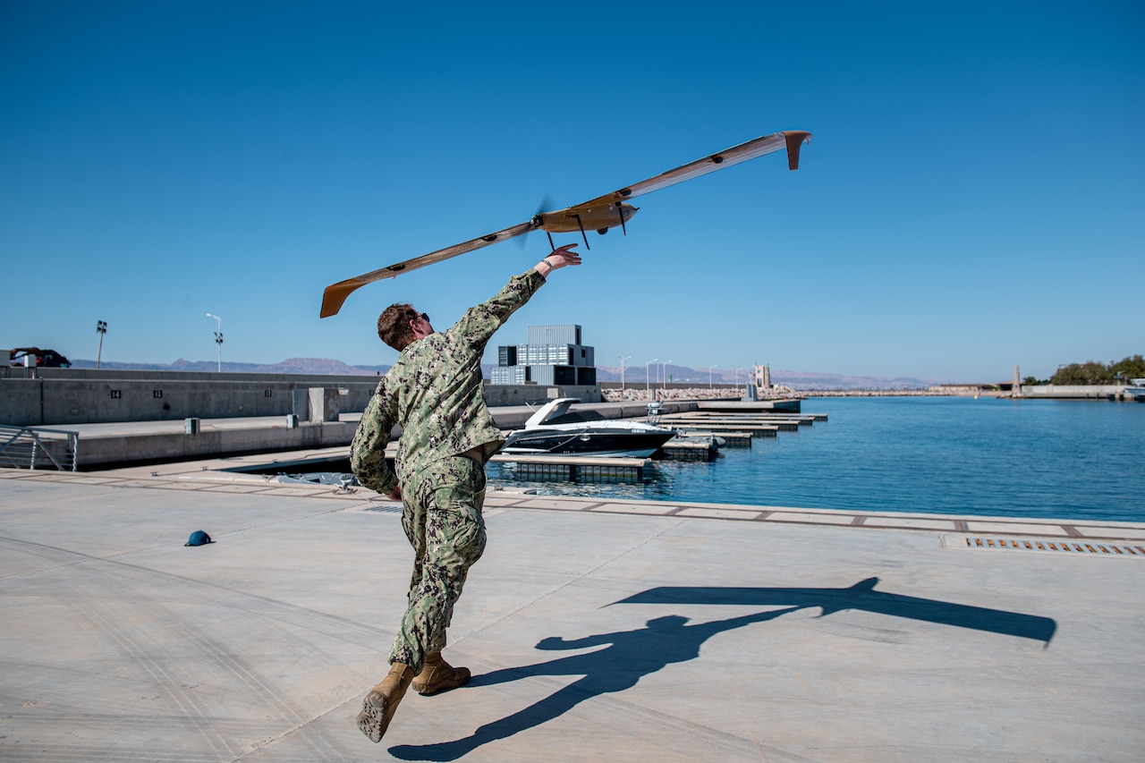 A sailor launches a drone.