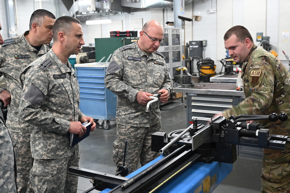 Staff Sgt. Michael Fisher, aircraft structural maintenance craftsman with the 169th Maintenance Squadron, South Carolina Air National Guard, demonstrates an industrial tube bender to Bulgarian air force officers at McEntire Joint National Guard Base, South Carolina March 5, 2022. Bulgaria, a NATO partner and partner with the Tennessee National Guard under the State Partnership Program, is scheduled to receive F-16 fighter jets. South Carolina assisted with the SPP engagement by hosting maintenance officers from the Bulgarian air force.