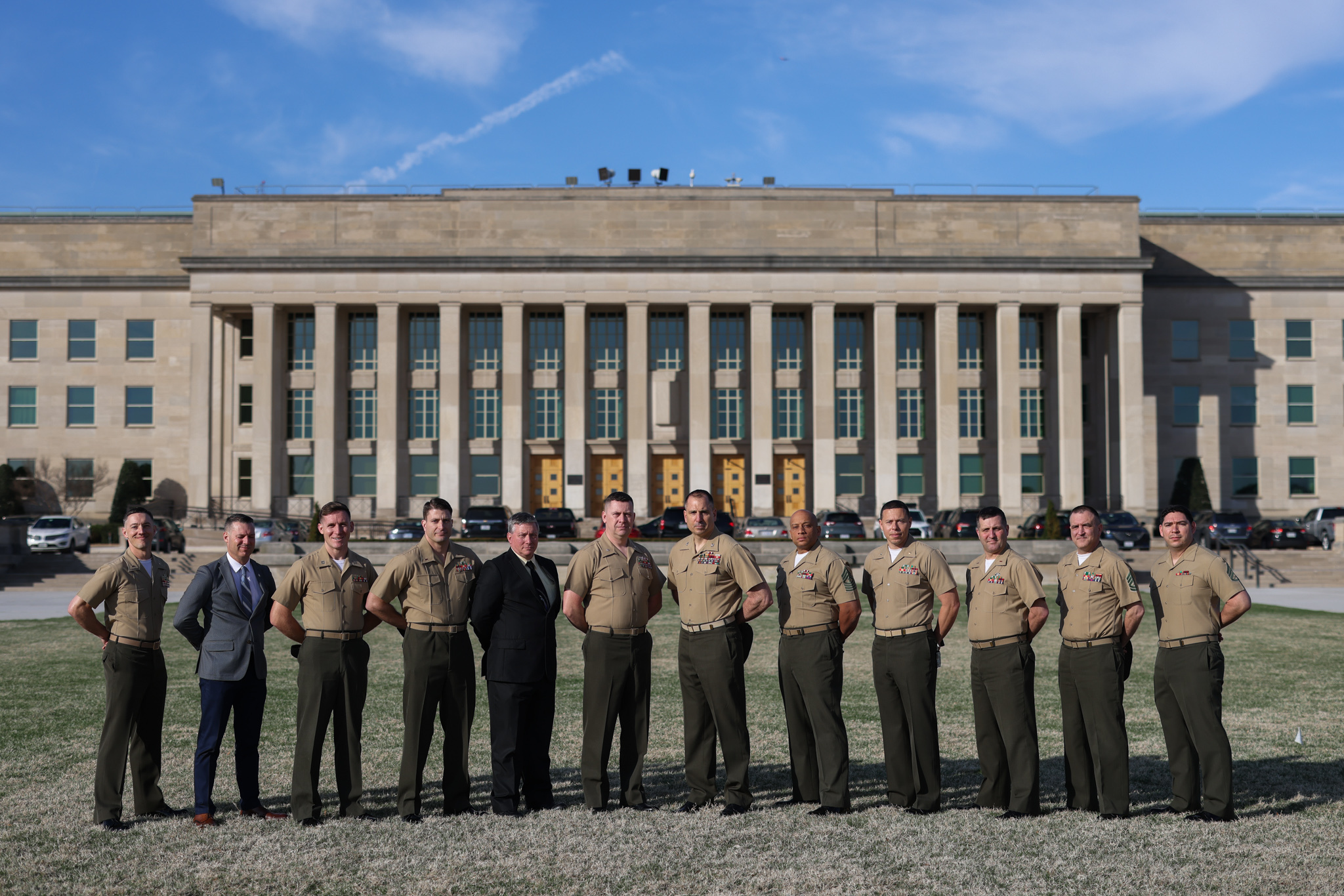 Marines standing in a row outside with their hands behind their backs.
