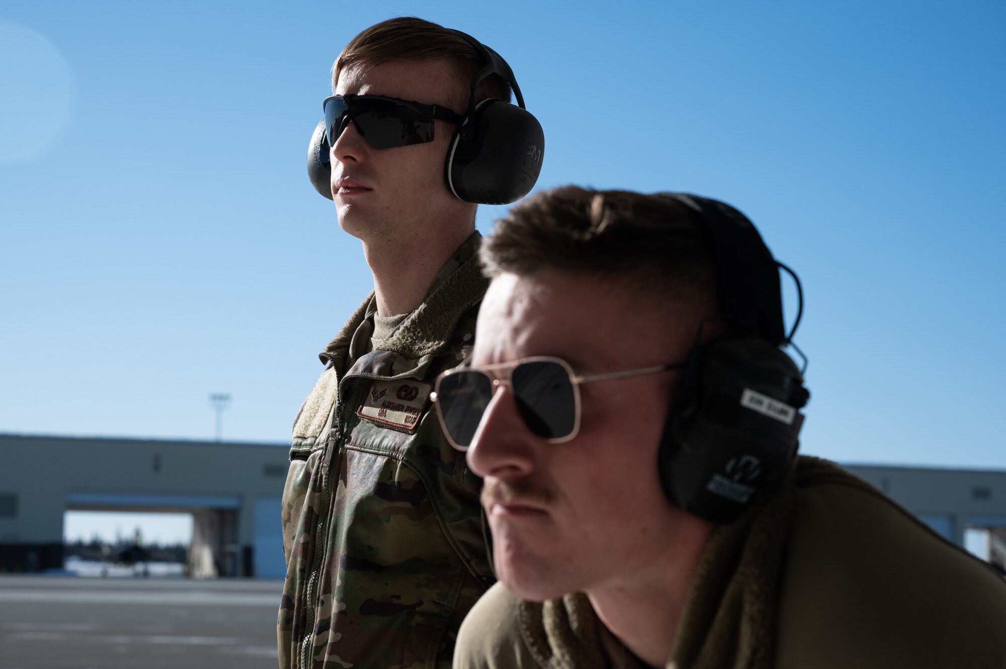 U.S. Air Force Senior Airman Aleksandr Zenski, a 354th Logistics Readiness Squadron vehicle maintenance journeyman (left), and Airman 1st Class Ian Spears, a 356th Aircraft Maintenance Unit crew chief, stand by during a ‘Crew Chief for a Day’ immersion on Eielson Air Force Base, Alaska, March 15, 2022.