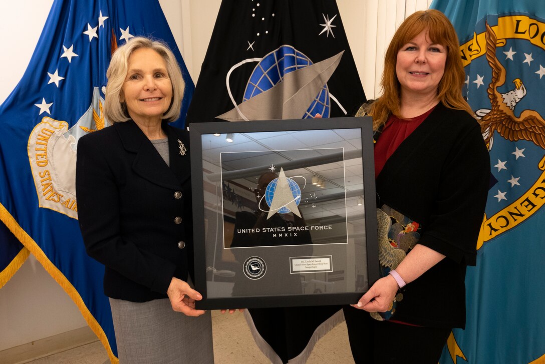 woman presents another a framed small flag