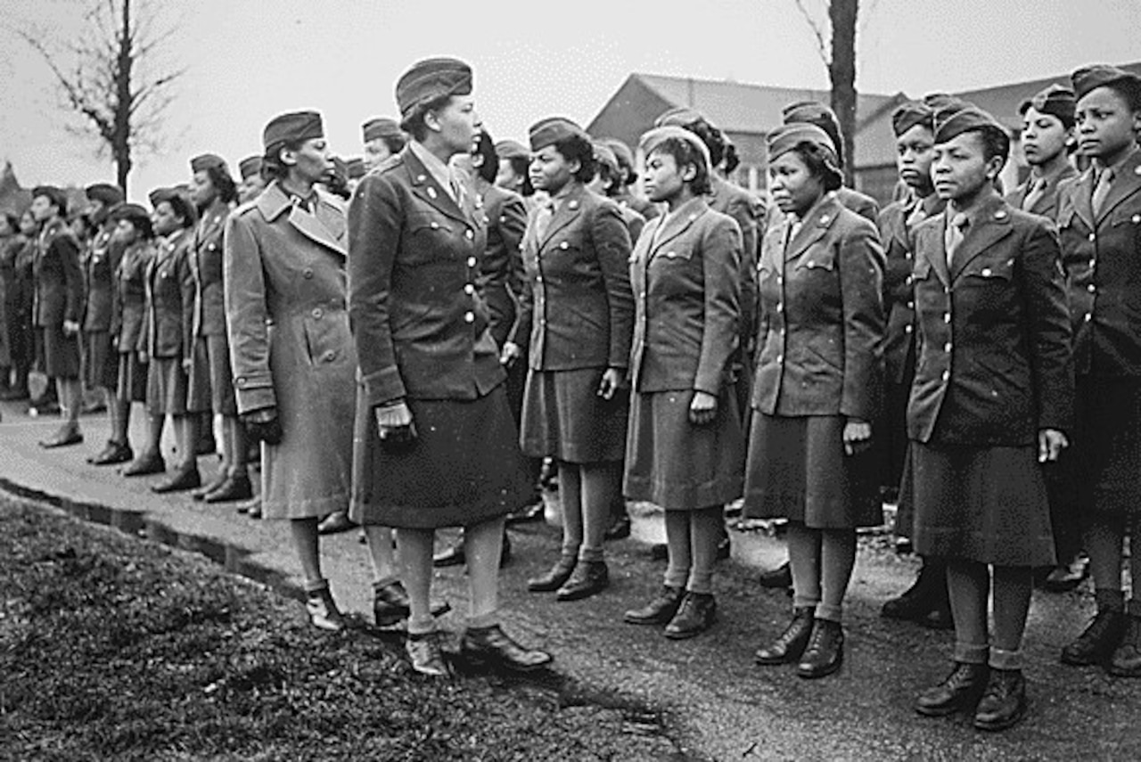 Two women view a line of uniformed women in formation.